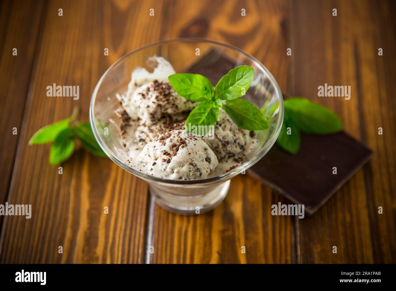 Hausgemachtes Eis mit Stücken geriebener dunkler Schokolade, in einer Schüssel auf einem Holztisch. Stockfoto