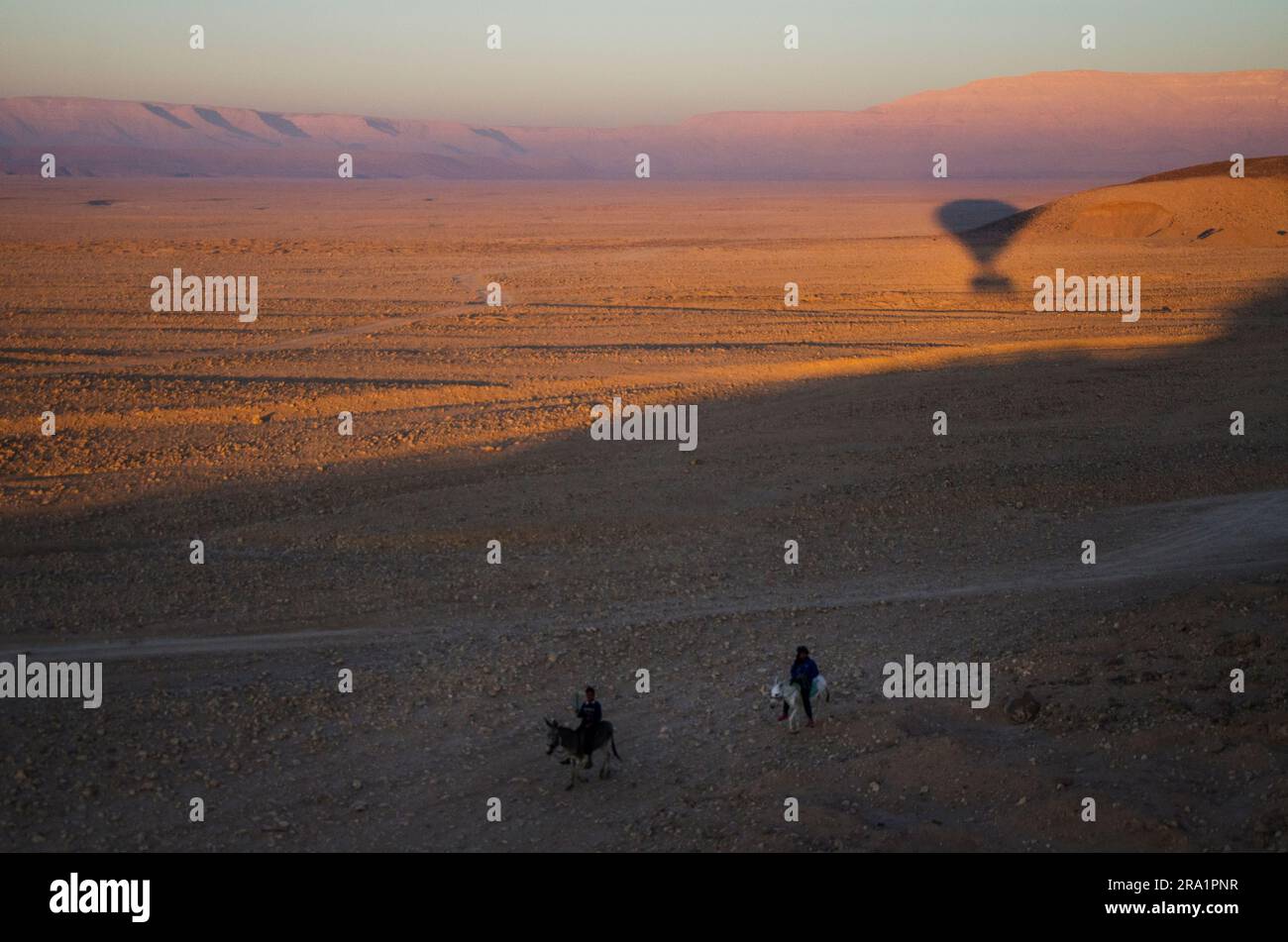 Zwei Kinder auf Eseln jagen einen Heißluftballon in der Sahara Stockfoto