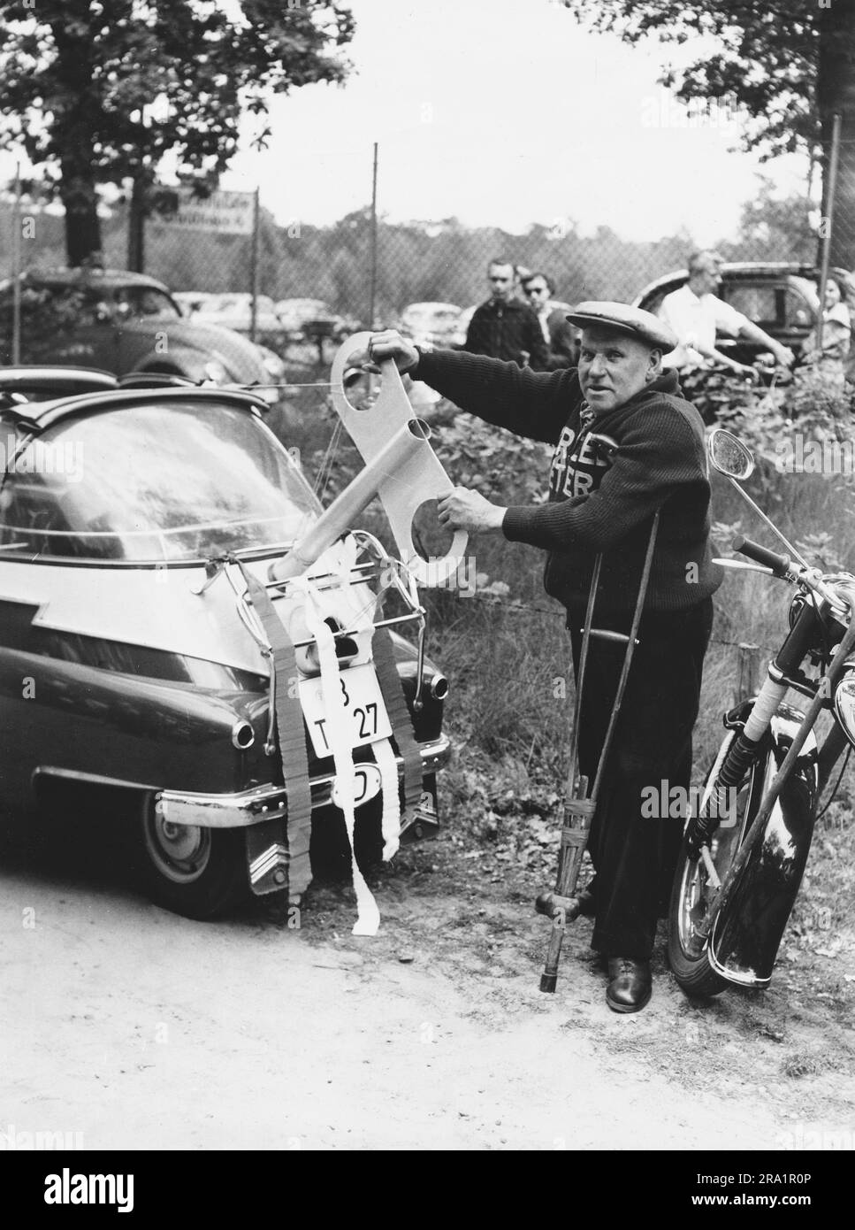 Das Berliner Original 'Krücke', bürgerlich Reinhold Habisch, zeiht mit Riesenschlüssel ein BMW Isetta auf. Berlin, Deutschland 1957. Stockfoto