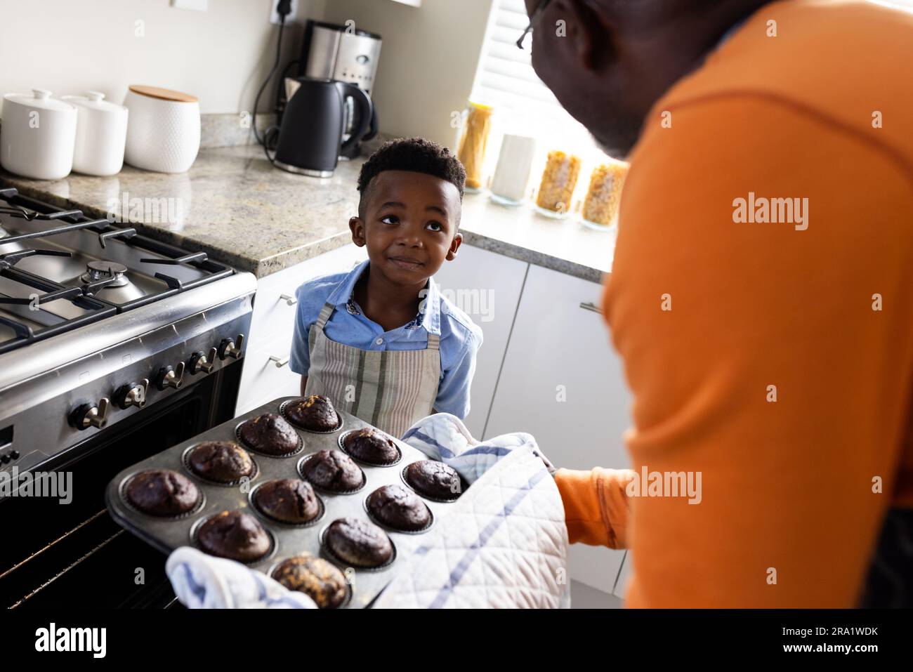 Fröhlicher afroamerikanischer Großvater und Enkel, die in der Küche backen, Zeitlupe Stockfoto