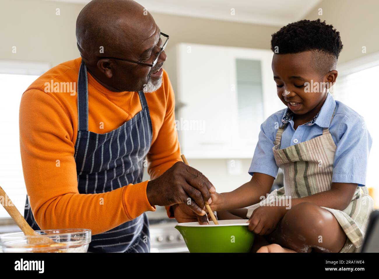 Fröhlicher afroamerikanischer Großvater und Enkel, die in der Küche backen, Zeitlupe Stockfoto