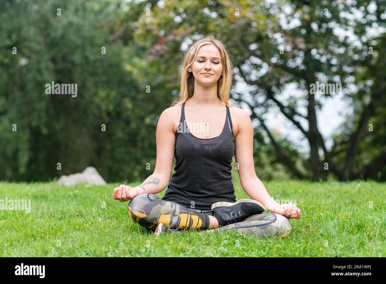 Weiß-blonde junge Frau meditiert im Freien in Berlin Stockfoto