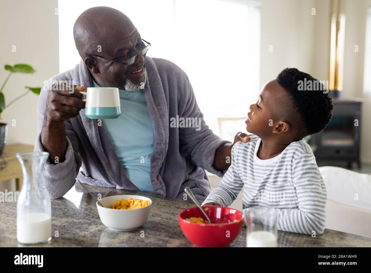 Glücklicher afroamerikanischer Großvater und Enkel frühstücken in der Küche Stockfoto