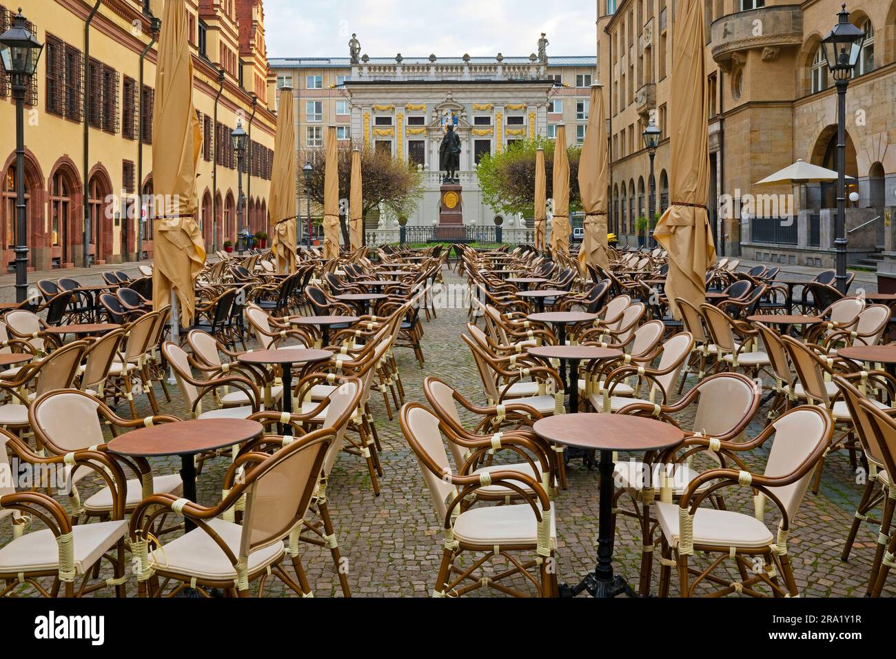 Am frühen Morgen leere Stühle und Tische auf dem Naschmarkt, Goethe-Denkmal und Alte Boerse im Hintergrund, Deutschland, Sachsen, Leipzig Stockfoto