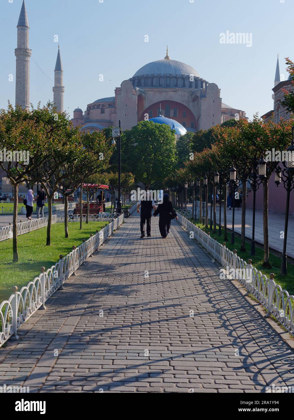 Muslimische Paare gehen auf einem Gartenweg in Richtung Hagia Sophia Moschee, Sultanahmet Viertel, Istanbul, Türkei Stockfoto