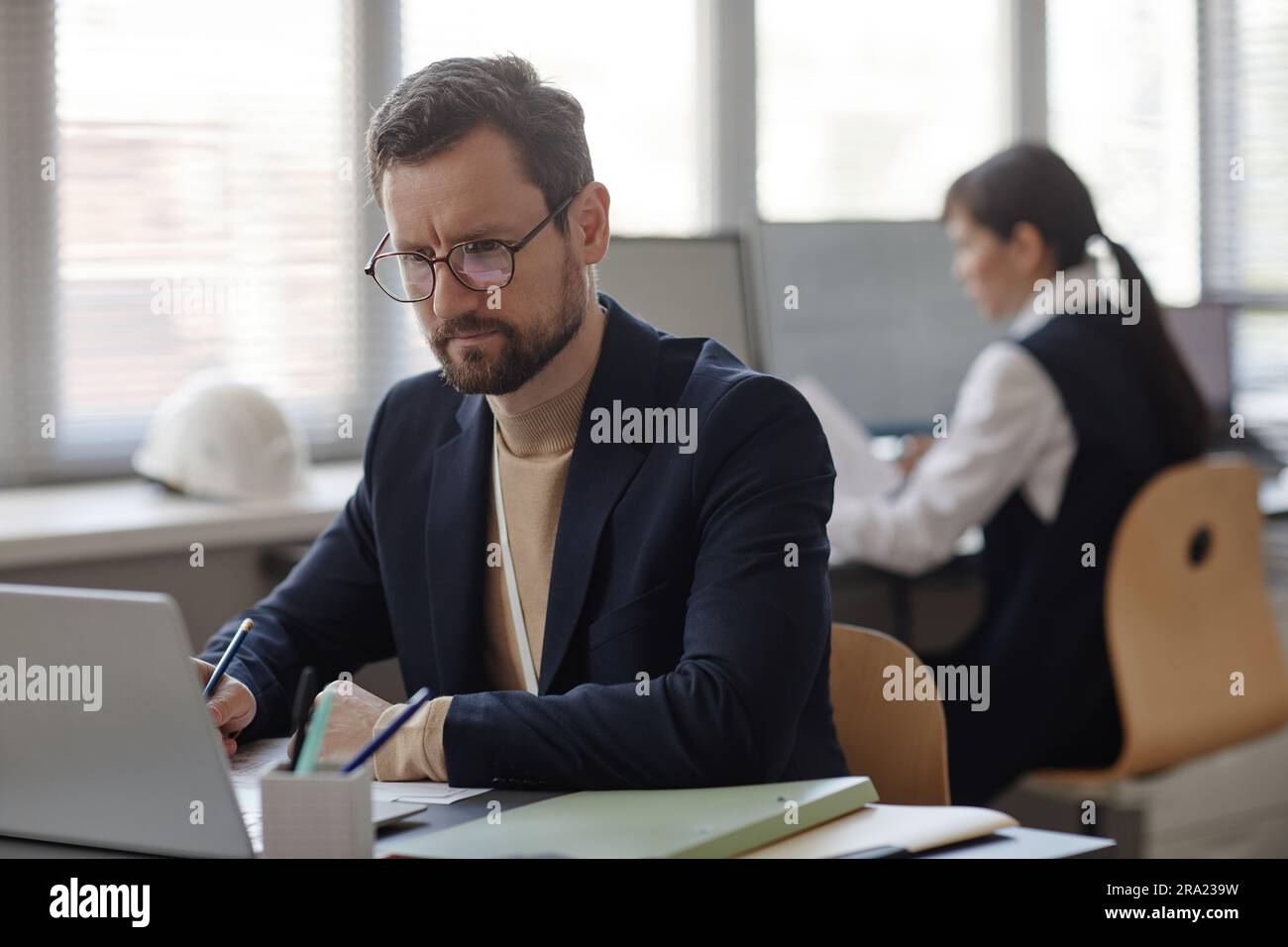 Porträt eines bärtigen Erwachsenen mit Brille und Laptop bei der Arbeit im Büro Stockfoto