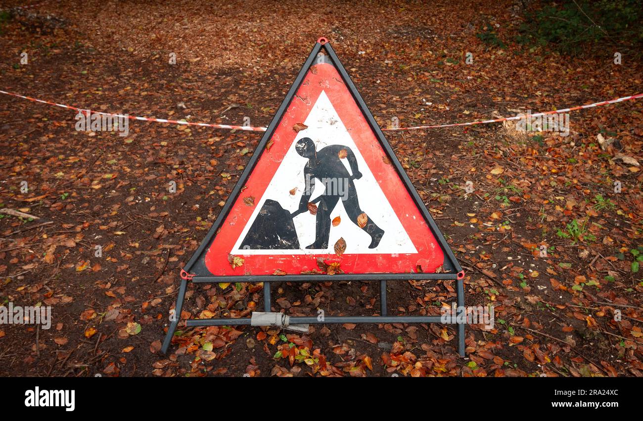 Straßenschild für Männer am Arbeitsplatz, mit Laub auf dem Boden. Stockfoto