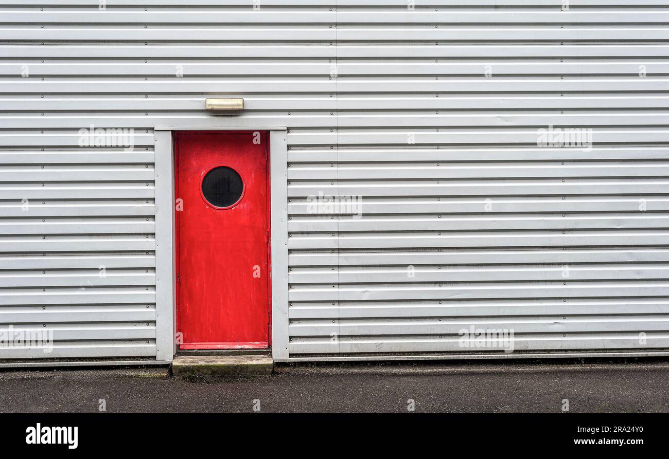Graues Industriegebäude mit roter Tür Stockfoto