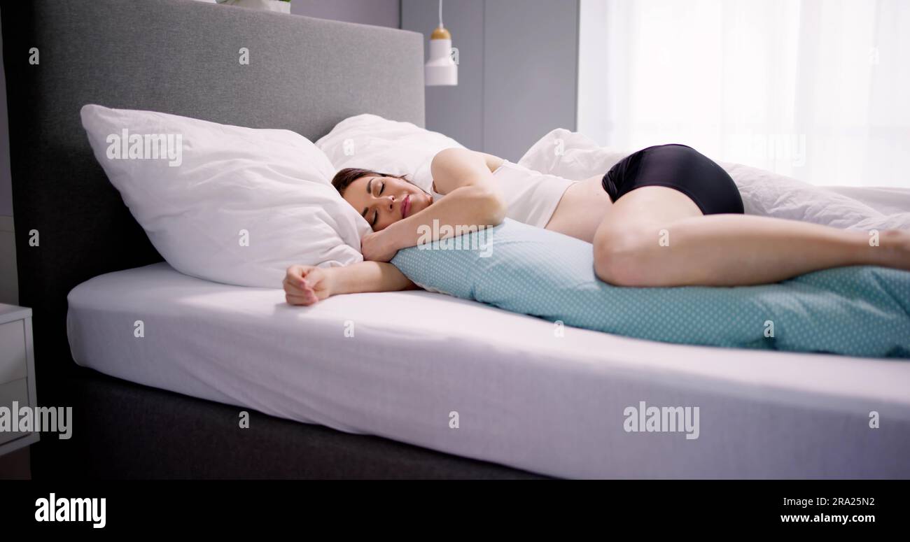 Schwangere Frau, Die Auf Einem Bett Mit Speziellem Kissen Schläft Stockfoto