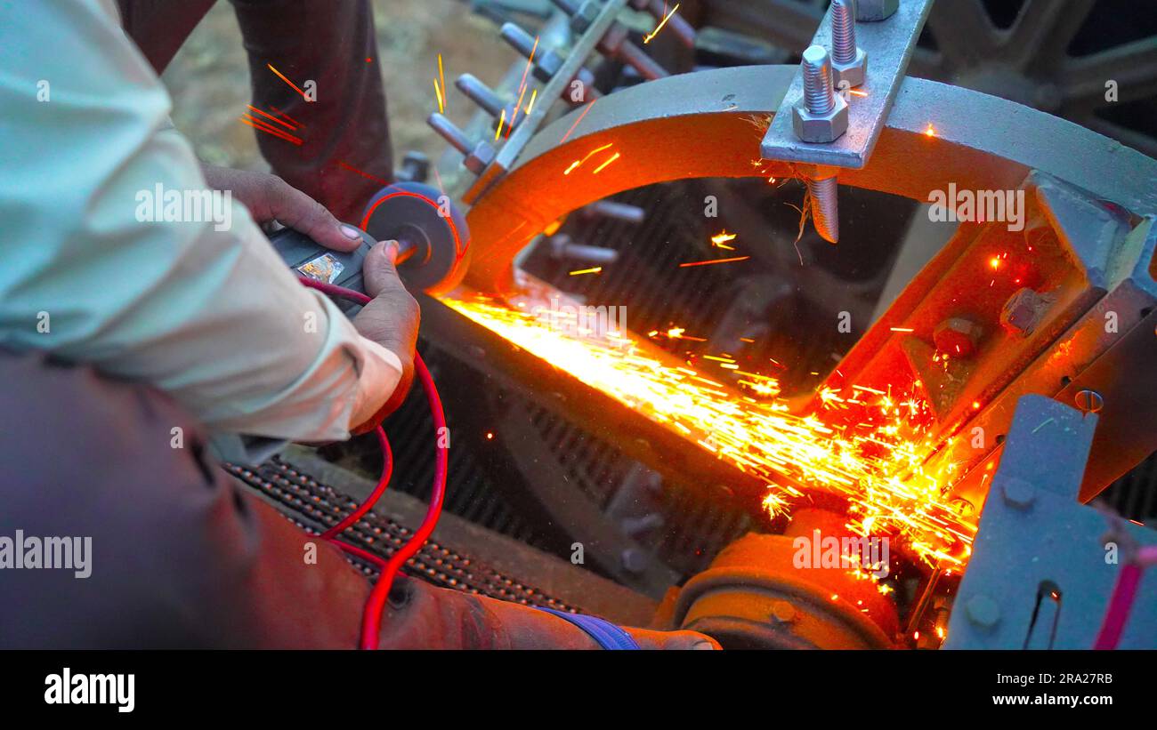 Arbeiter, der den Winkelschleifer in der Landwirtschaft verwendet und Funken wirft, Industriearbeiter, der Metall mit dem Schleifer schneidet. Viele glühende Funken Stockfoto