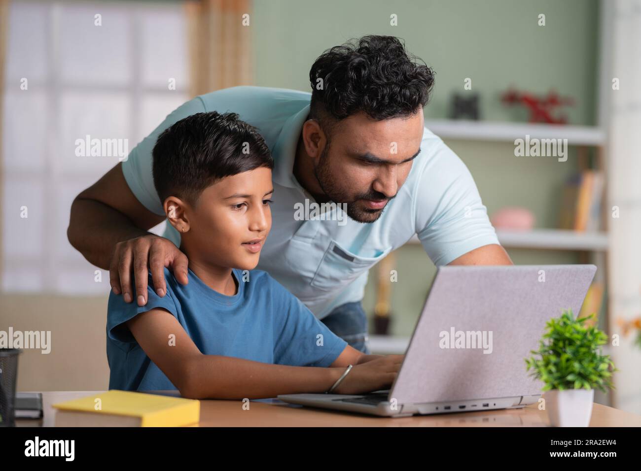 Indischer Vater erklärt oder unterrichtet vom Laptop bis zum Sohn zu Hause - Konzept von Familienunterstützung, Heimunterricht und Hausaufgaben-Unterstützung Stockfoto