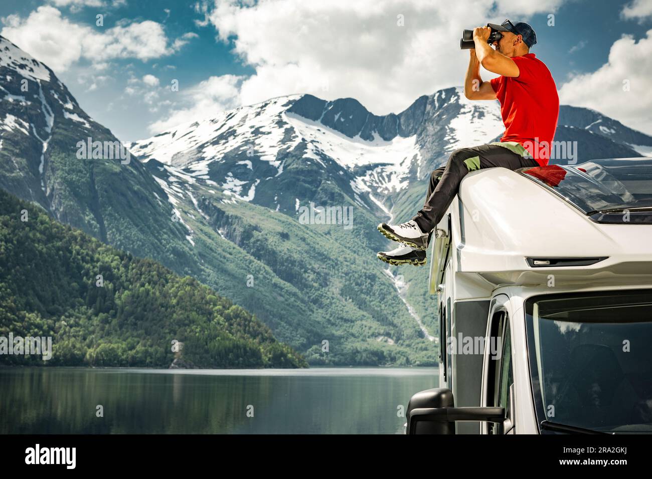 Weißer Mann in seinen 40s Jahren erkundete die norwegische Natur mit Ferngläsern, während er auf dem Dach seines Wohnmobils Platz nahm. Norwegen, Stockfoto