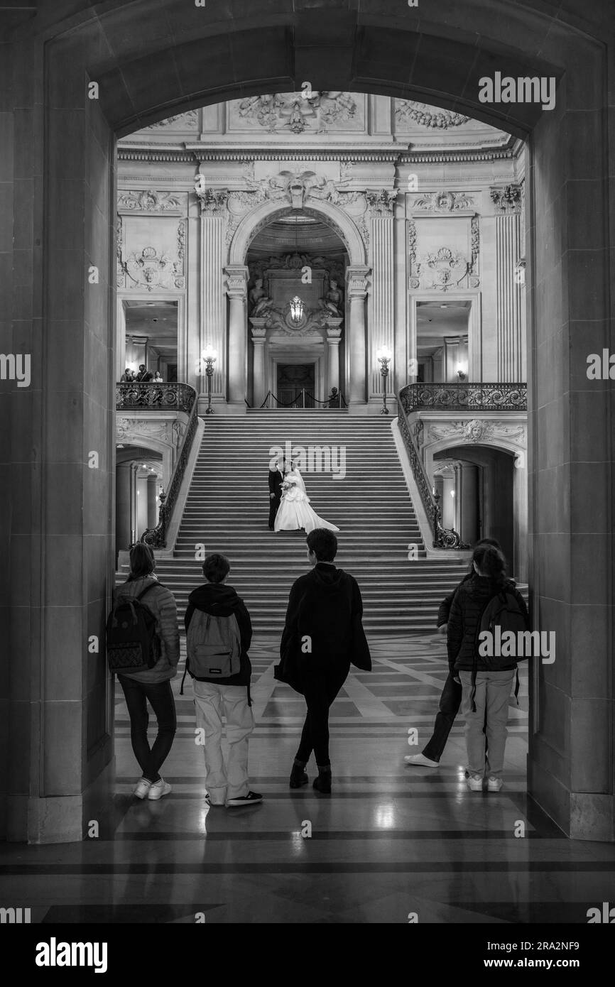 Leute, die ein Hochzeitspaar beobachten, wie es Fotos im Rathaus, San Francisco, USA, macht Stockfoto
