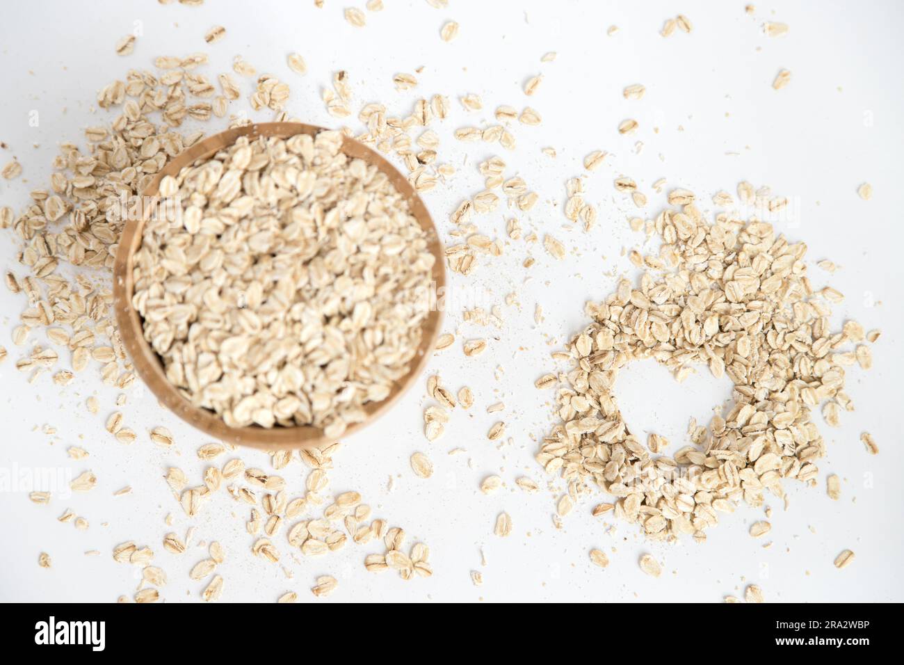 Holzschüssel mit Haferflocken auf weißem Hintergrund. Supernahrung mit hohem Nährstoffgehalt, die für mehrere Rezepte verwendet werden kann. Gesunde Ernährung. Draufsicht. Stockfoto