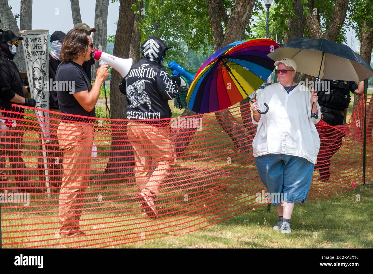 HUDSON, WI, USA - 17. JUNI 2023: Unidentifizierte maskierte Anti-LGBTQ+-Demonstranten und Festivalbesucher bei der Hudson-Pride-Feier. Stockfoto