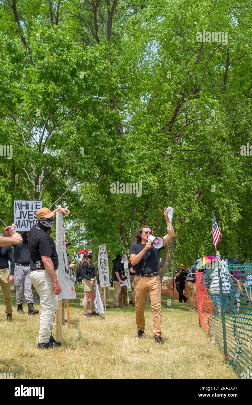 HUDSON, WI, USA - 17. JUNI 2023: Unidentifizierte maskierte Anti-LGBTQ+-Demonstranten und Festivalbesucher bei der Hudson-Pride-Feier. Stockfoto