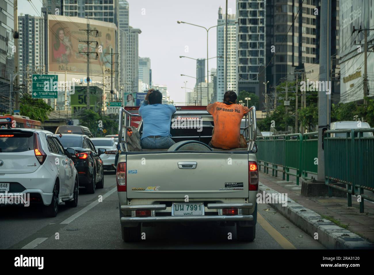 Thailändische Bauarbeiter, die zur Arbeit zurückkehren, werden am späten Nachmittag im Stau auf der Ratchadaphisek Road in Bangkok auf dem Bett eines Pick-up-Lkws gesehen. In Thailand ist es üblich, dass Arbeiter auf der Ladefläche von Pickup-Lkws transportiert werden, was häufig mit der Landwirtschaft und dem Baugewerbe in Verbindung gebracht wird, auch wenn dies aufgrund der Sicherheitsrisiken nicht empfohlen wird und nach den thailändischen Verkehrsgesetzen illegal ist. Stockfoto