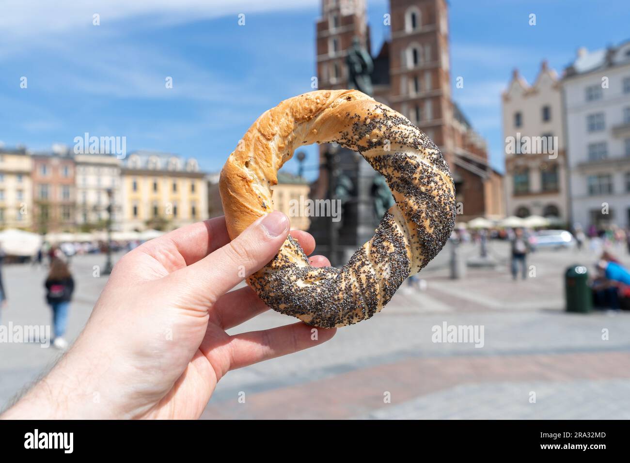 Halten Sie eine Obwarzanek-Krakowski-Brezel auf dem Krakauer Marktplatz. St. Marienkirche in Bg. Krakowskie obwarzanki Food in Krakau, Polen. Stockfoto