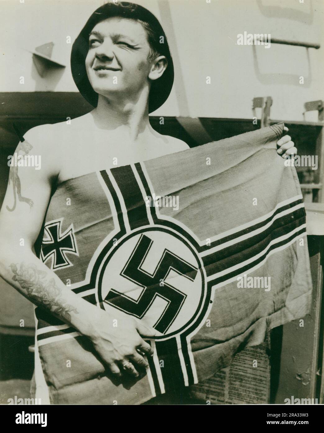 Nazi-Flagge von U-805 gefangen. Dieses Foto zeigt einen Seemann mit einer Nazi-Flagge, die von U-805 gefangen wurde. 1945-05-01T00:00:00. Nordostregion (Boston, MA). Fotodruck. Abteilung der Marine. Erster Marinebezirk. Büro des stellvertretenden Stabschefs für Verwaltung. Büro des Historischen Offiziers. Ca. 1941-ca. 1946. Die Verwaltungsgeschichte des ersten Marinestreifens im Zweiten Weltkrieg Stockfoto