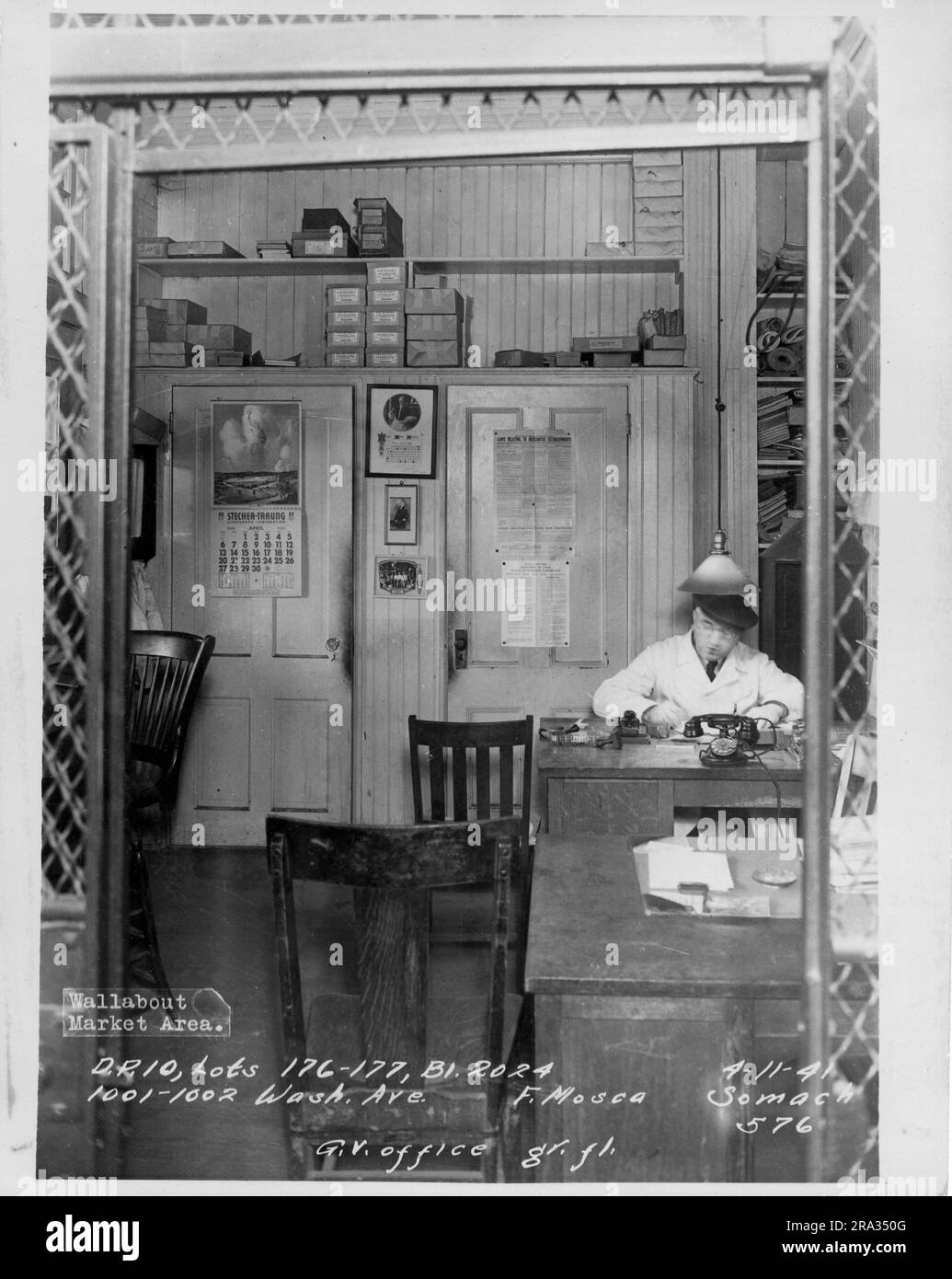 Foto des Wallabout Market, D.P. 10, Lots 176-177, Building 2024, 1001-1002 Washington. Ave., F. Mosca, G.V. Büro gr.fl. Blick auf das Büro mit einem Mann mit Kappe am Schreibtisch und Telefon von Minus 576.. Stockfoto