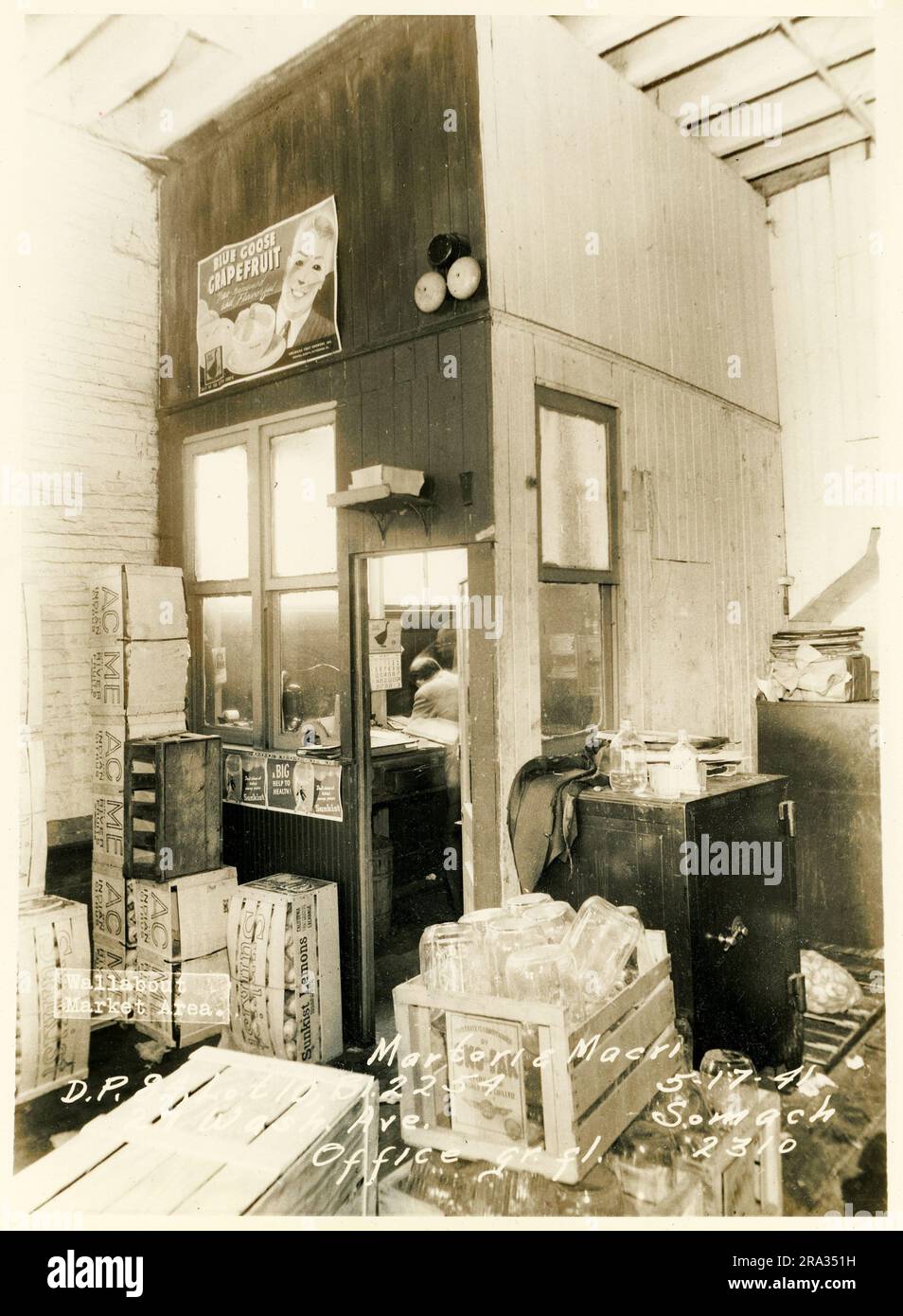 Foto von Interior Wallabout Market, D.P. 84, Los 10, Bl. 2254, 27 Wash. Ave. Martori & Macri Office gr. fl... Detaillierter Blick auf die Außenseite der Büroabtrennung mit Safe, Kisten, Beschilderung Blue Goose Grapefruit, Kalender, Alramglocken, Glasflaschen und Mann im Büro, vom Negativen 2310.. Stockfoto
