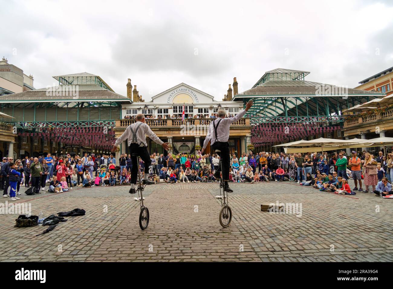 Covent Garden, ein beliebter Londoner Platz mit Straßenkünstlern, die ein Einrad oder ein Einrad fahren, und die Menschenmassen lachen, während sie ihre Show vorführen. Stockfoto
