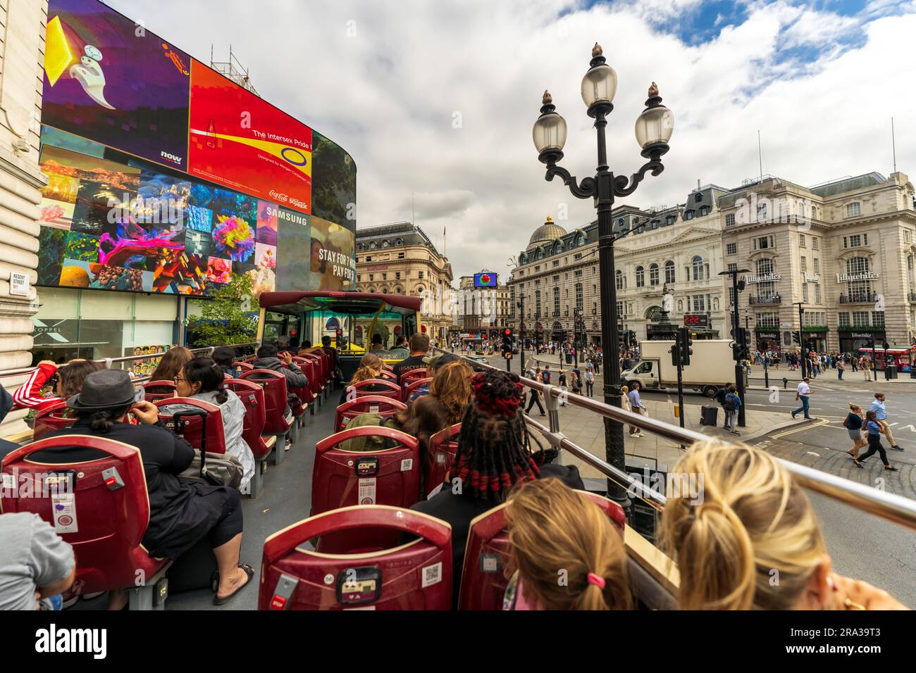 Touristen fahren in einem berühmten roten Doppeldeckerbus durch den Piccadilly Circus, einen berühmten belebten Platz in London. Beste Aussicht auf die Stadt vom offenen Bus. Stockfoto