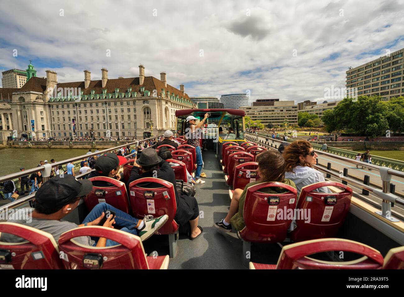 Roter Doppeldeckerbus mit offenem Oberdeck, Hop-on-Hop-off-Busfahrt über die Themse, Touristen besichtigen Londons wichtigste Sehenswürdigkeiten, historische Stätten und erhalten einen Blick auf die Skyline der Stadt. Stockfoto
