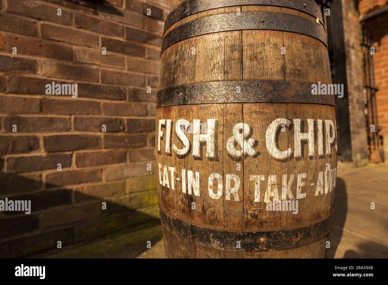 Ein traditionelles englisches Pub-Schild mit der Werbung für Fish and Chips zum Essen im Restaurant, zum Mitnehmen. Das Schild ist auf einem Holzfass gemalt und hat ein nostalgisches Aussehen Stockfoto