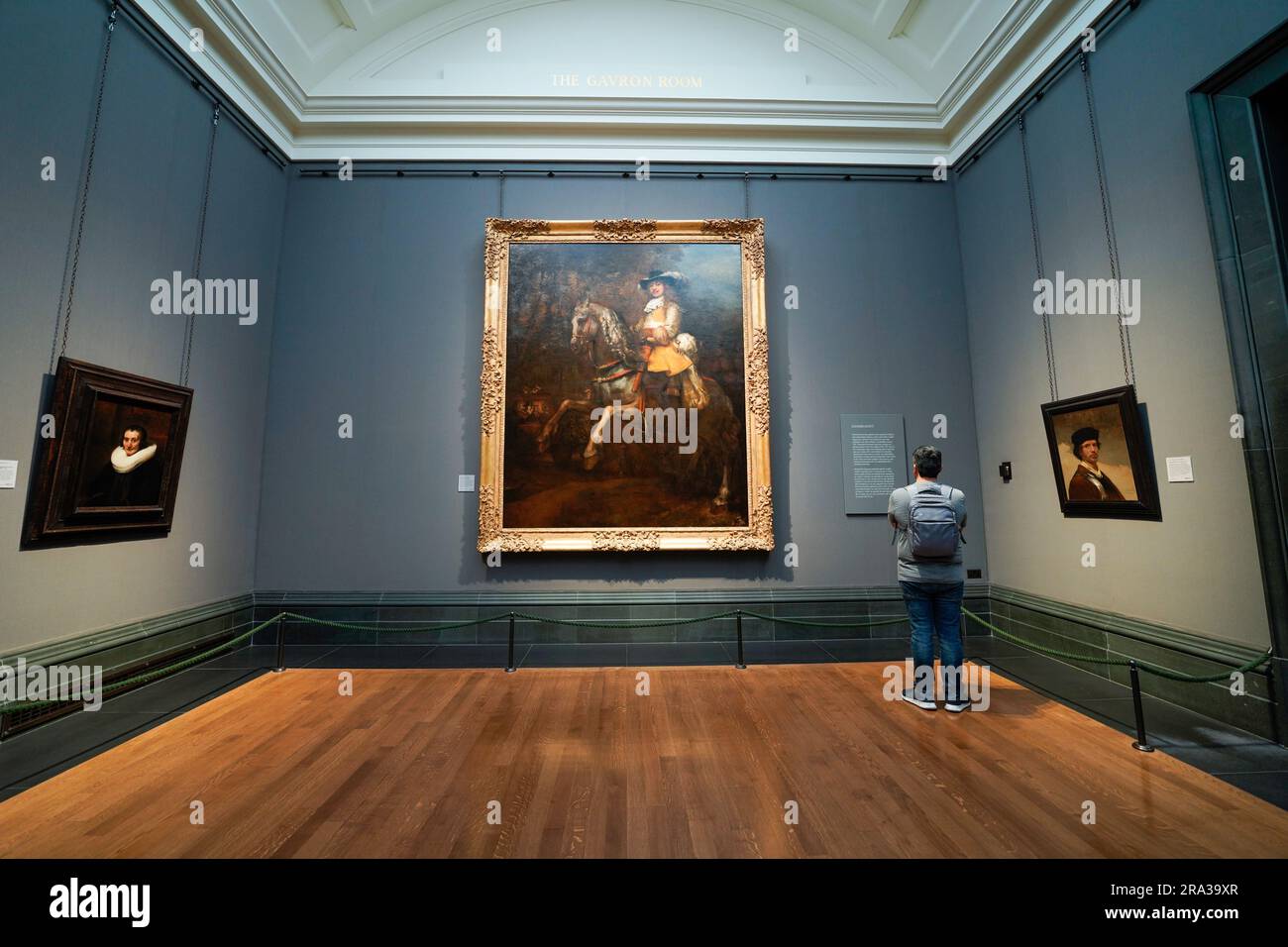 Die National Gallery in London, ein Mann, der die Beschreibung eines Rembrandt-Gemäldes liest, ein Meisterwerk. Das Kunstmuseum befindet sich am Trafalgar Square. Stockfoto