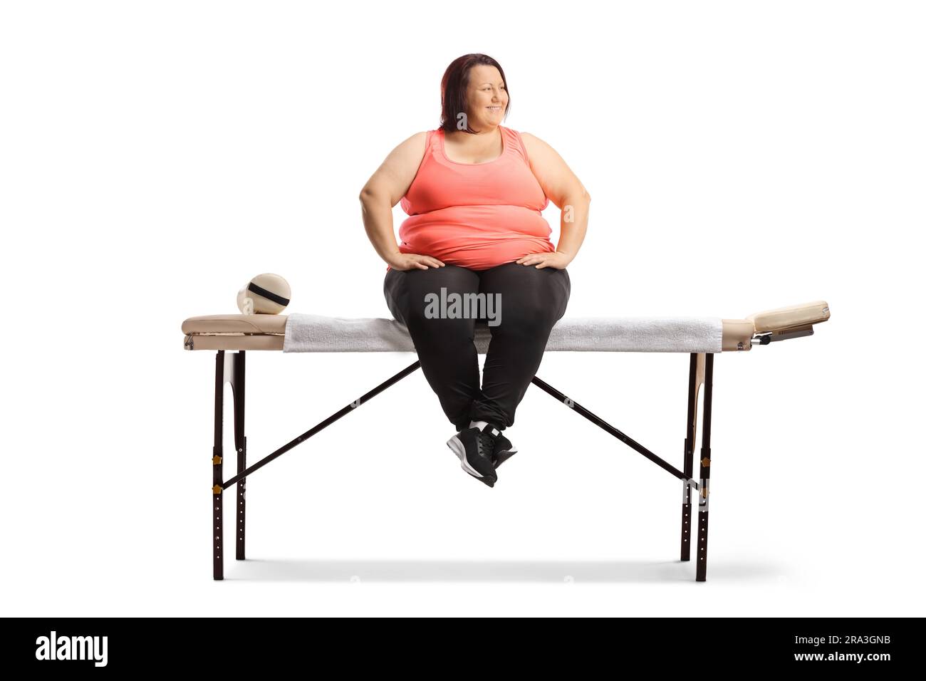 Übergewichtige Frau, die zur Physiotherapie auf einem Bett sitzt, isoliert auf weißem Hintergrund Stockfoto