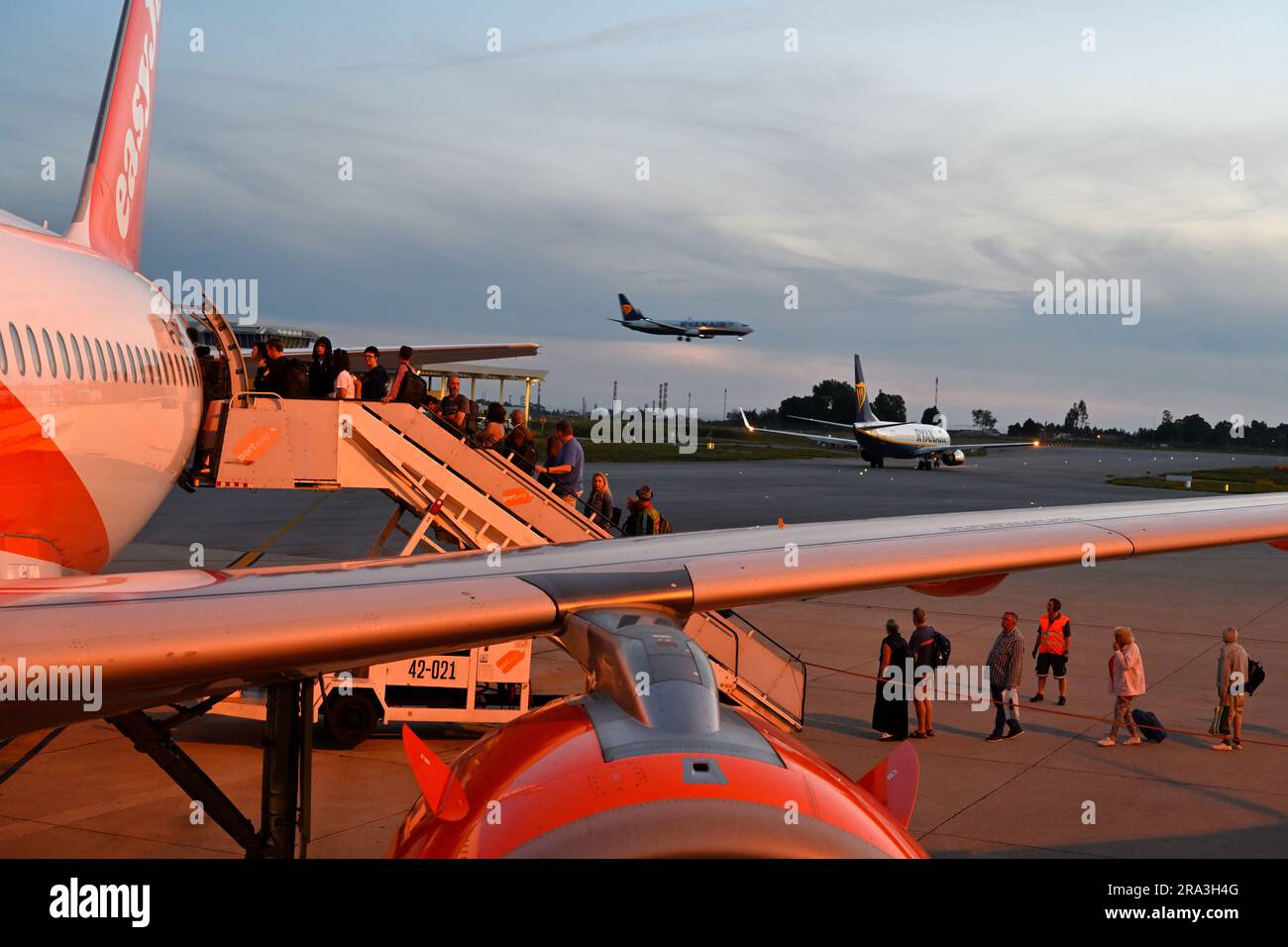 Am Abend, easyJet Flugzeug mit Passagieren, die hinten einsteigen, mit einem anderen Flugzeug, das an Land kommt und das dritte auf der Landebahn, Flughafen Porto, Portugal Stockfoto