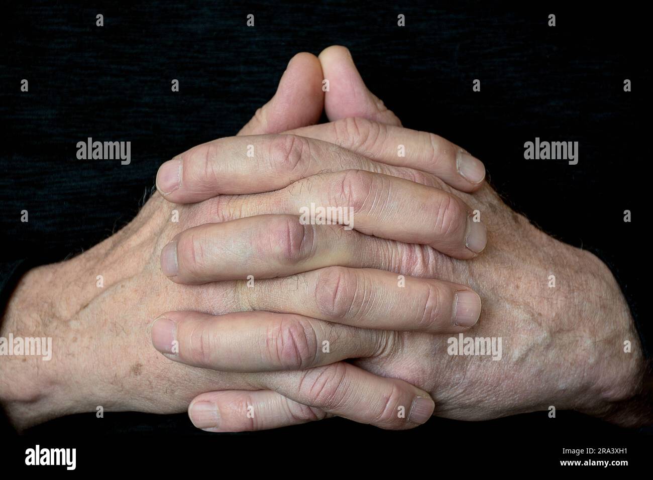 Nahaufnahme der Hände eines Weißen, gefaltet im Gebet auf schwarzem Hintergrund Stockfoto