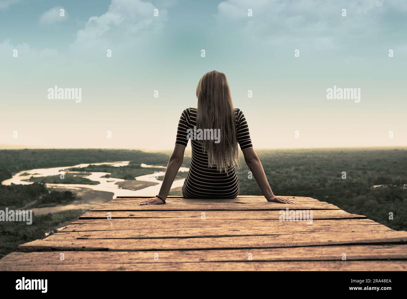 Eine Frau, die vor einem Aussichtspunkt in Richtung Dschungel sitzt Stockfoto