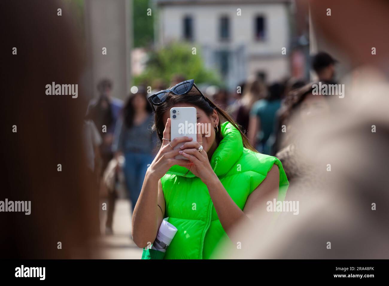 Mailand, Italien - 22. April 2023: Junge Frau in grüner ärmelloser Jacke, die während der Ausstellung des Milan Design Wee ein Foto mit ihrem Handy macht Stockfoto