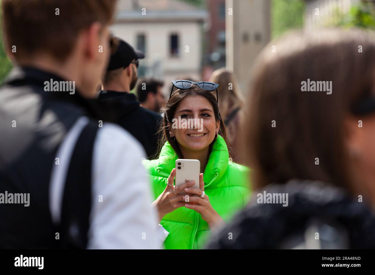 Mailand, Italien - 22. April 2023: Junge Frau in grüner ärmelloser Jacke, die während der Ausstellung des Milan Design Wee ein Foto mit ihrem Handy macht Stockfoto