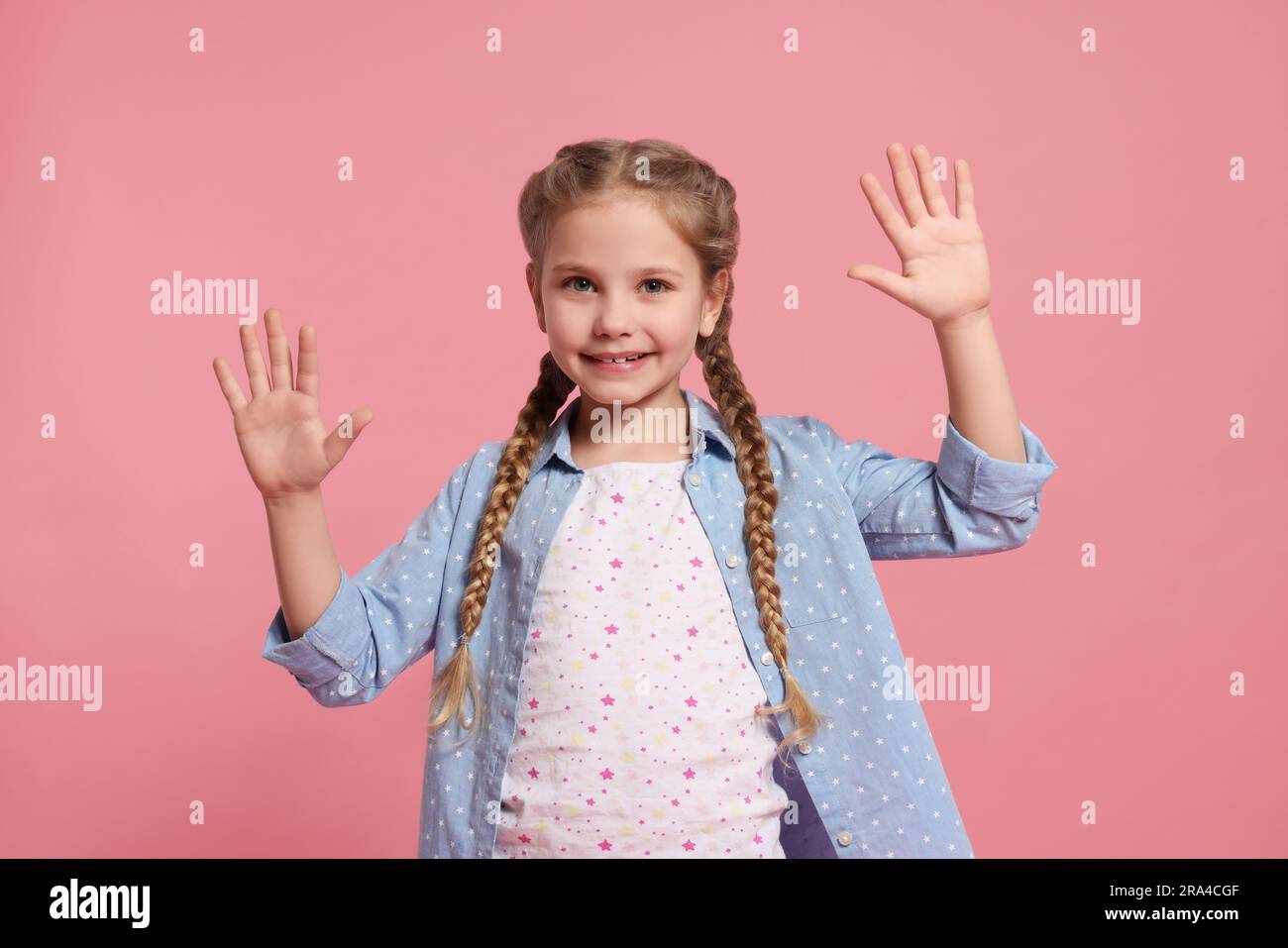 Glückliches Mädchen gibt High Five mit beiden Händen auf pinkfarbenem Hintergrund Stockfoto