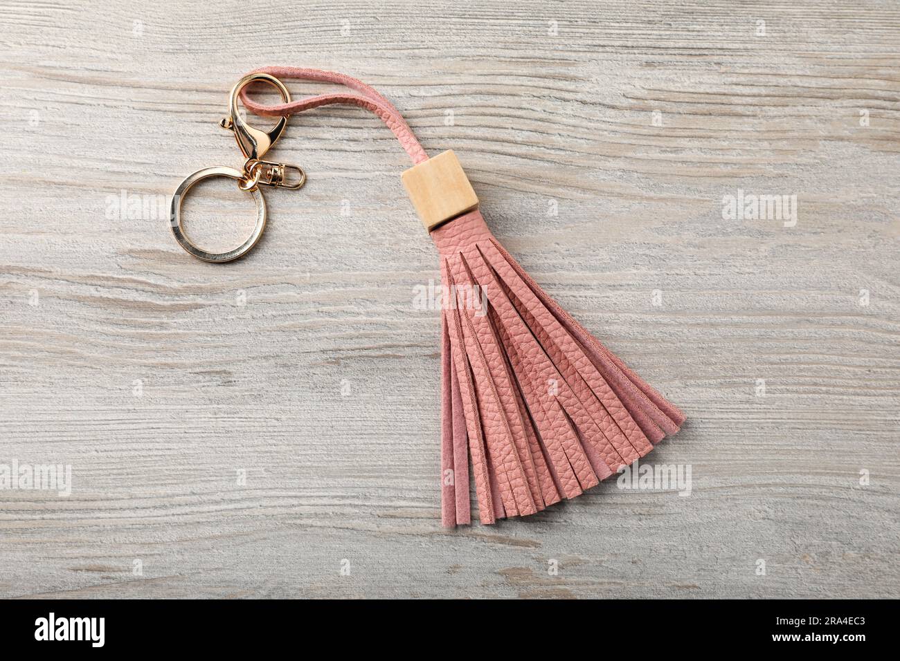 Schlüsselanhänger aus rosafarbenem Leder auf hellem Holzhintergrund, Draufsicht Stockfoto
