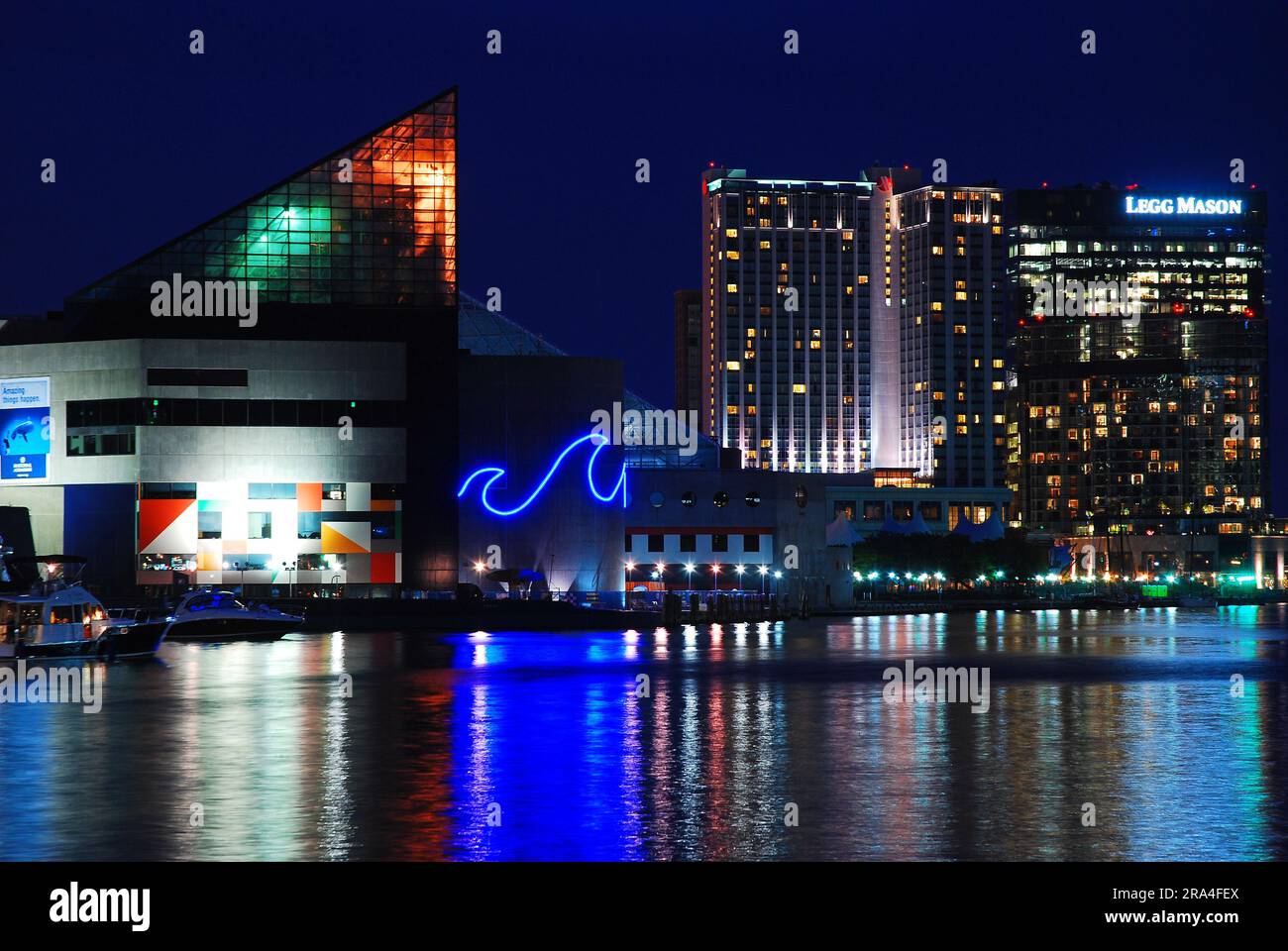 Das National Aquarium und die Skyline von Baltimore, Maryland, spiegeln sich bei Nacht in den Gewässern des Binnenhafens wider Stockfoto