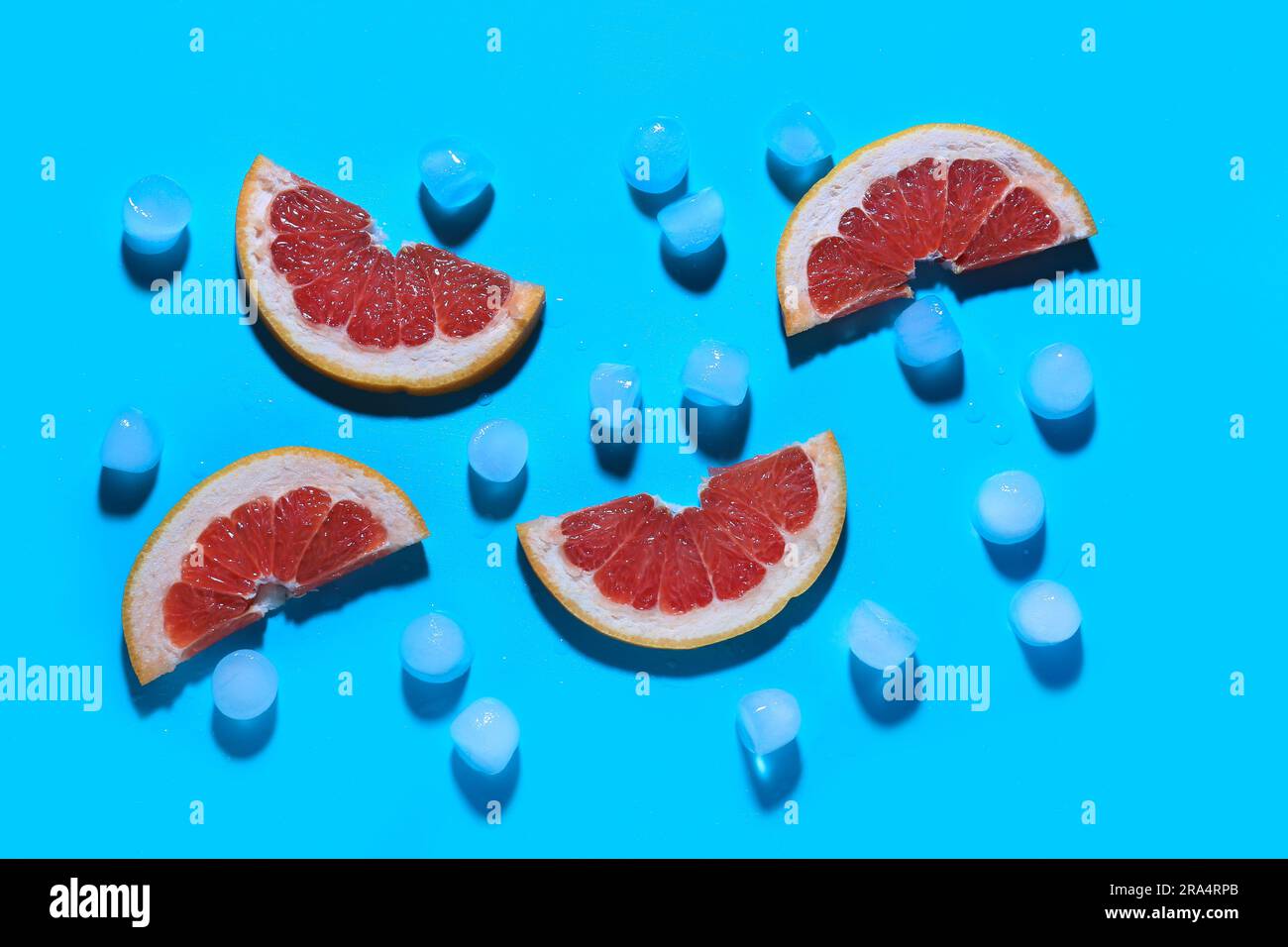 Grapefruitscheiben mit Eiswürfeln auf blauem Hintergrund Stockfoto