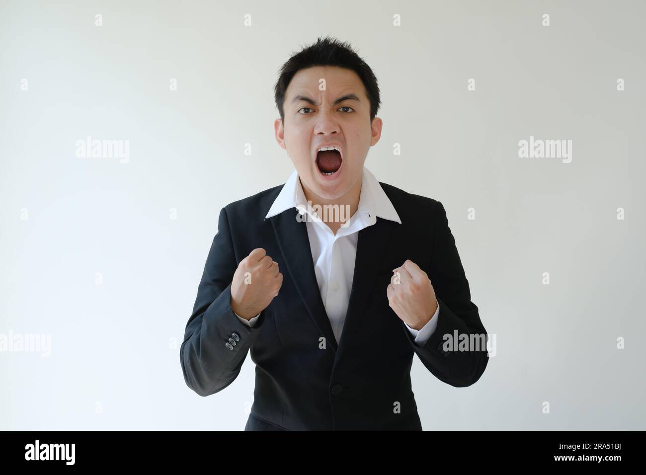 Junger asiatischer Geschäftsmann mit aufgeregtem Gesichtsausdruck und Blick in die Kamera. Isolierter weißer Hintergrund. Stockfoto