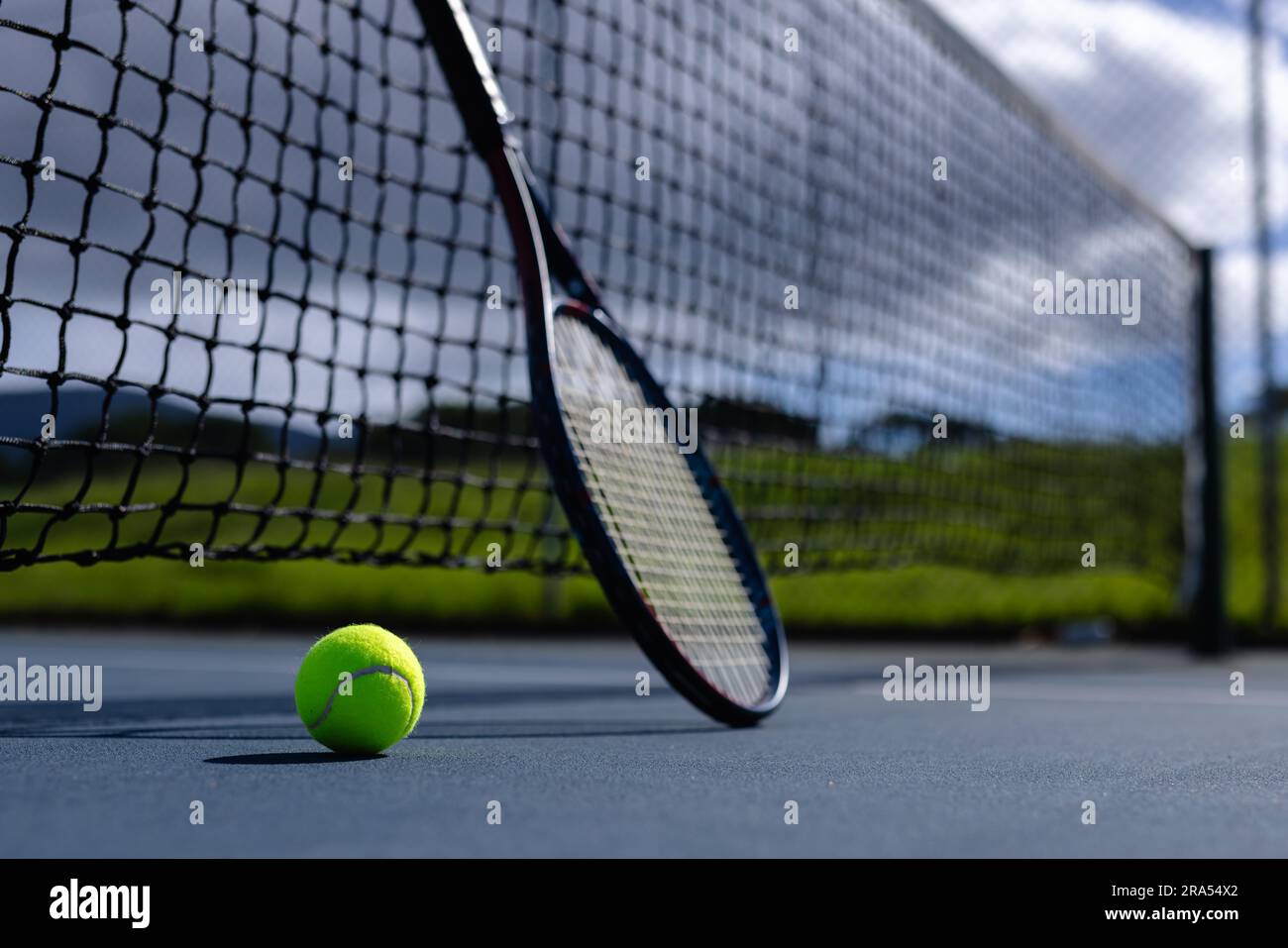 Nahaufnahme von Tennisball und Tennisschläger gegen Netz auf dem Tennisplatz an sonnigen Tagen, Kopierbereich Stockfoto
