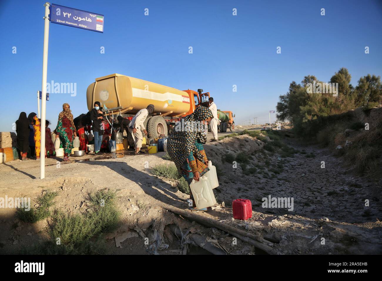 EINGEREICHT - 21. Juni 2023, Iran, Zabol: Dieses im Mai 2023 aufgenommene undatierte Bild zeigt die Bewohner, die Wasser von einem Tanker in der Nähe des ausgetrockneten Lake Hamun holen. Die iranische Provinz Sistan und Baluchistan ist von Dürre und Wasserknappheit betroffen. Die Bewohner der Grenzregion zwischen Afghanistan und dem Iran leiden unter brennender Hitze, Dürre und Sandstürmen. Manchmal ist das Wasser in den Provinzen so knapp, dass es mit Tankern in die Dörfer gebracht wird. Jetzt wurde die Region Ende Mai Schauplatz eines blutigen Gefechts, als ein Schusswechsel die Grenzregion in ein Schlachtfeld verwandelte. Nur wenige Tage zuvor, Stockfoto