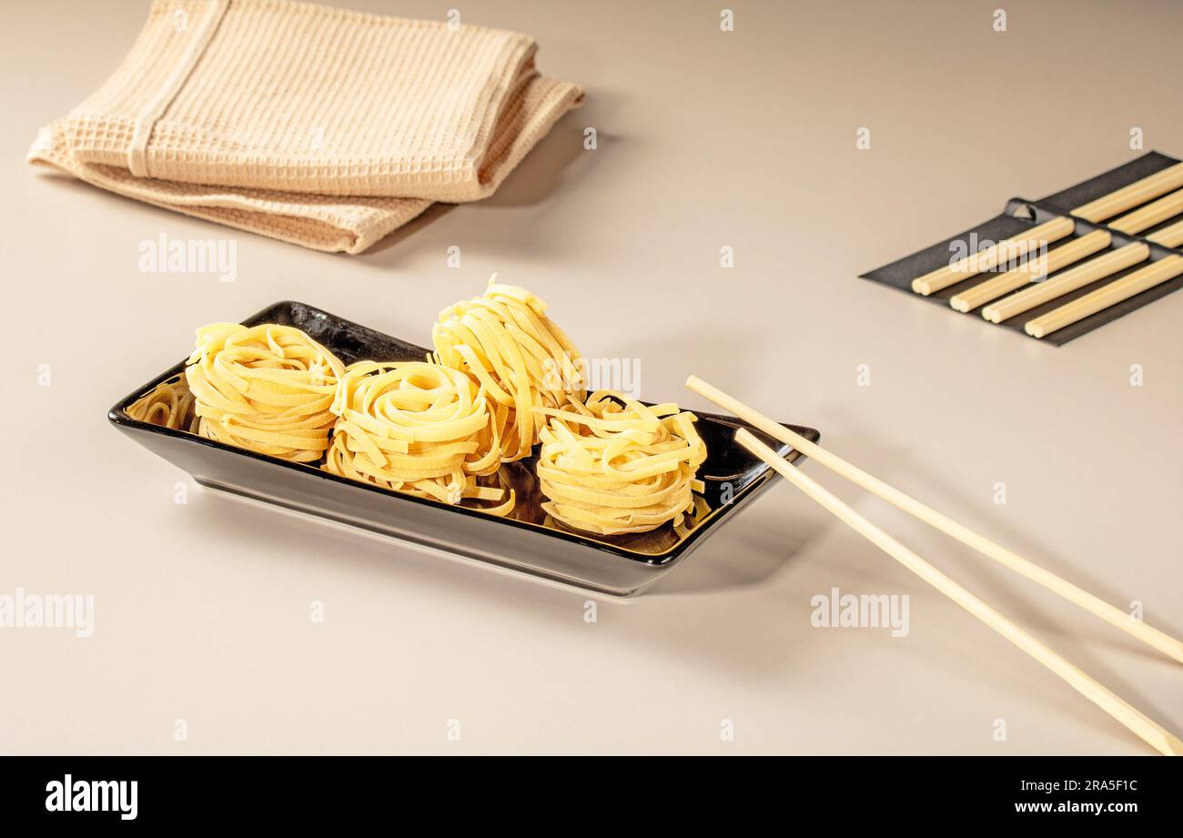 Chinesische Nudeln auf schwarzem Teller und Bambusstäbchen. Stockfoto