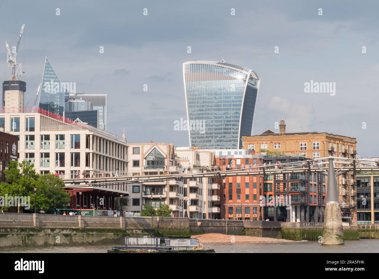 Menschen, die die Millenium Bridge mit Rafael Viñoly Walkie Talkie Wolkenkratzer und der Londoner Skyline im Hintergrund überqueren, London, England, Großbritannien Stockfoto