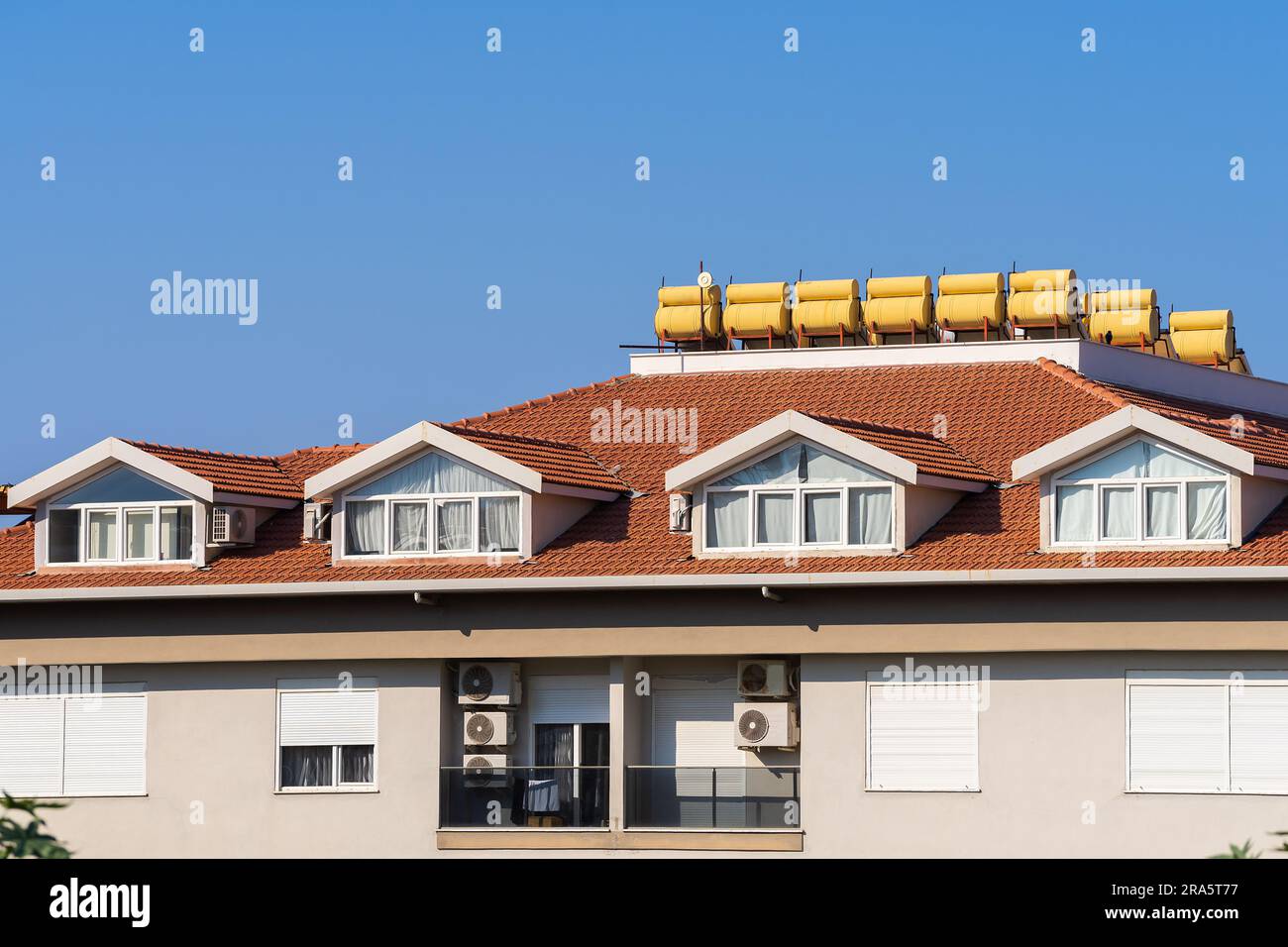 Das Dach eines Mehrfamilienhauses mit installierten Solar-Warmwasserbereitern. Der Himmel ist klar. Stockfoto