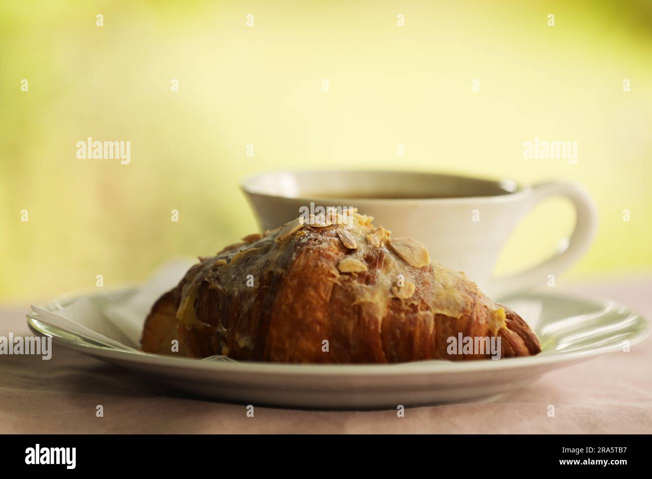 Ein Mandelcroissant und eine Tasse Kaffee Stockfoto