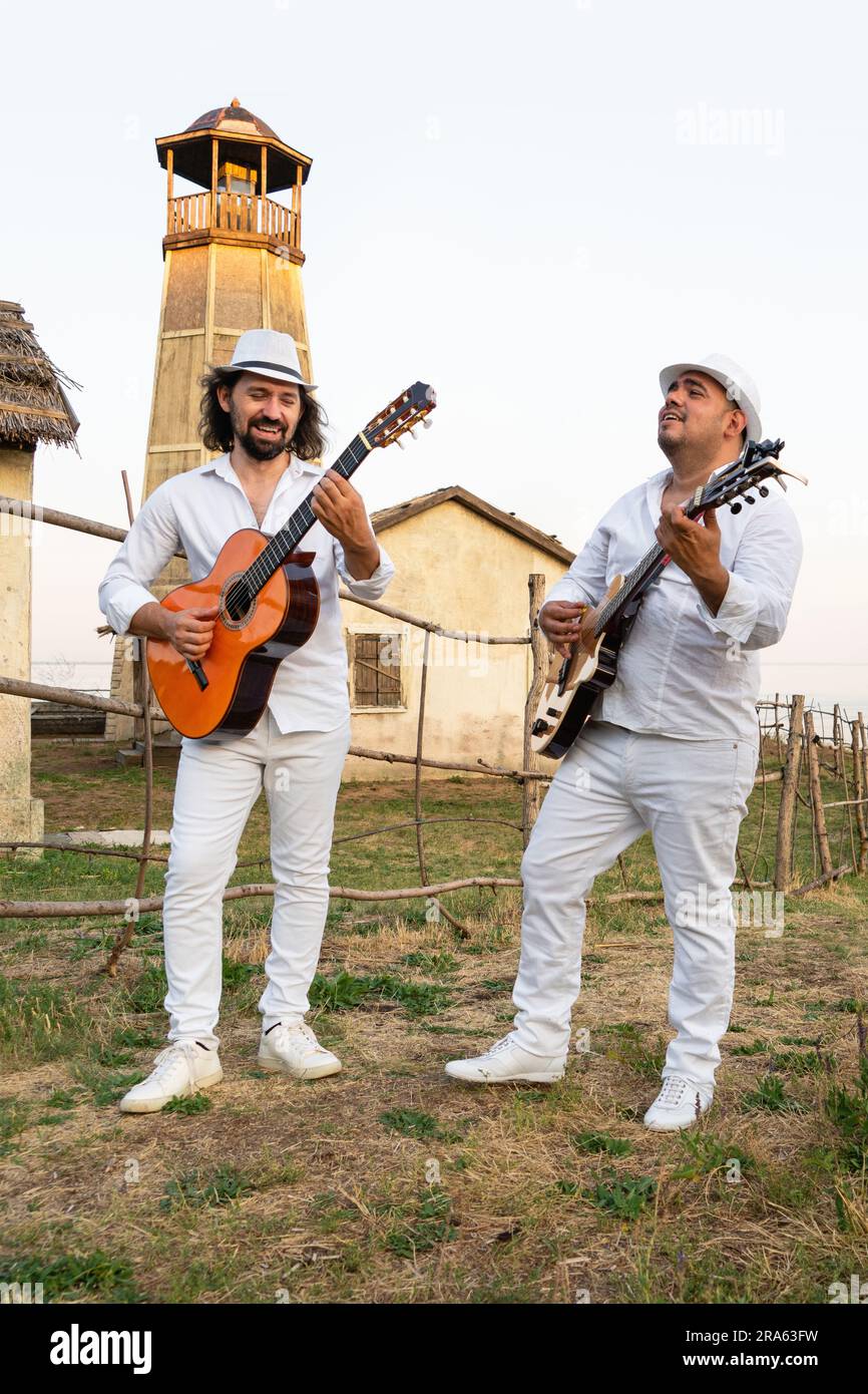 Musiker in weißen Kleidern und weißen Hüten spielen Gitarren. Stockfoto