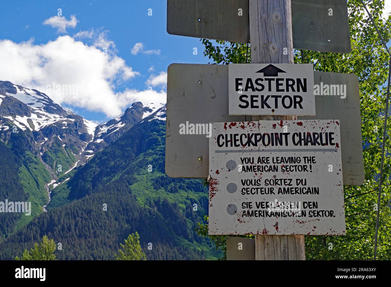 Ein Schild weist darauf hin, dass der östliche Sektor verlassen wird, hohe Berge im Hintergrund, Checkpoint Charlie, Geisterstadt Hyder, Alaska, USA Stockfoto