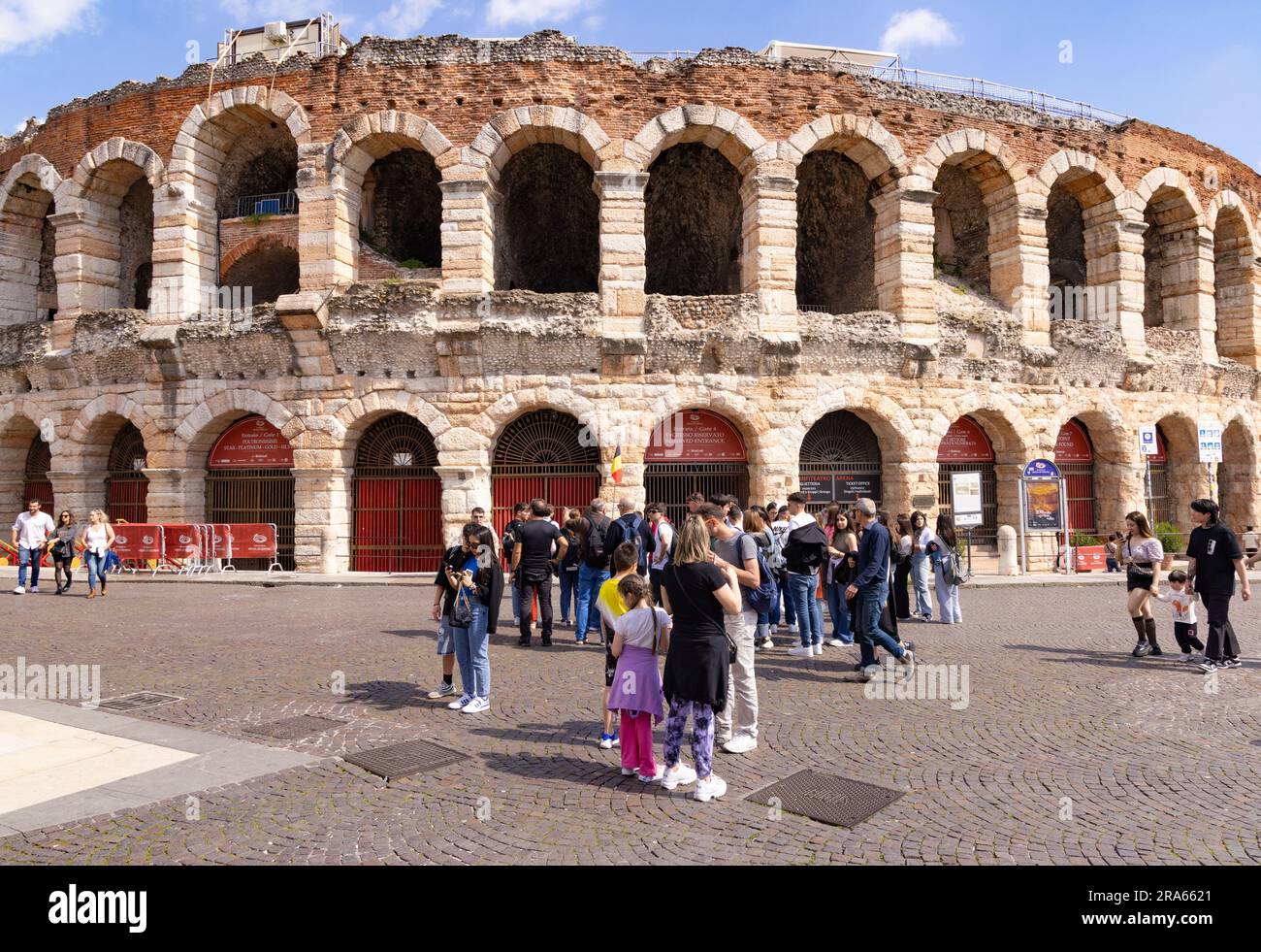 Tourismus in Italien; Touristen außerhalb der Verona Arena, einem römischen Amphitheater aus dem 1. Jahrhundert; in der Frühlingssonne Piazza Bra, Verona, Veneto, Italien Europa Stockfoto